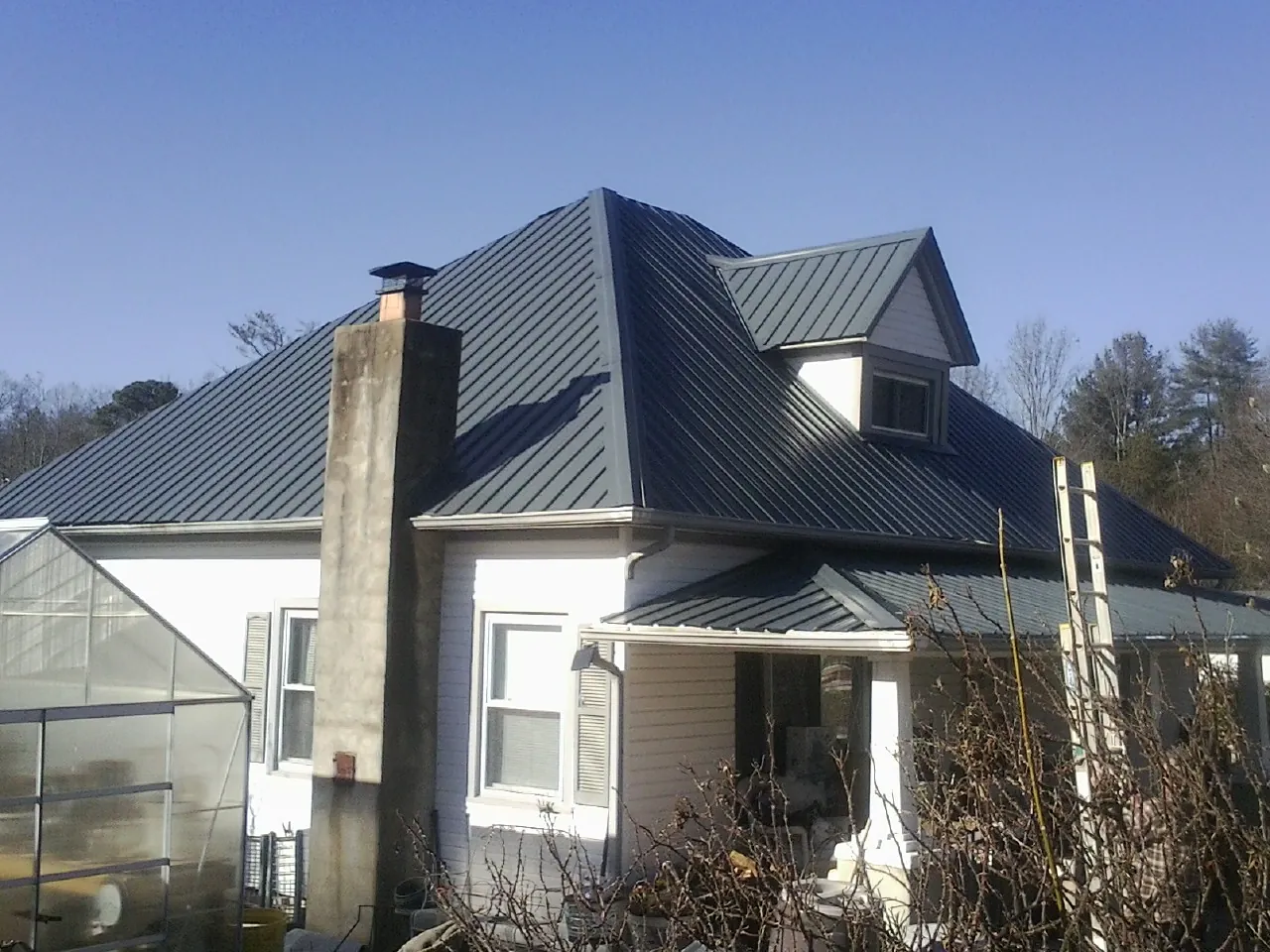 Dark blue standing seam metal roof on a white farmhouse with dormer — Slate & Tile Roof Repair by Roofing Brothers in South Acworth