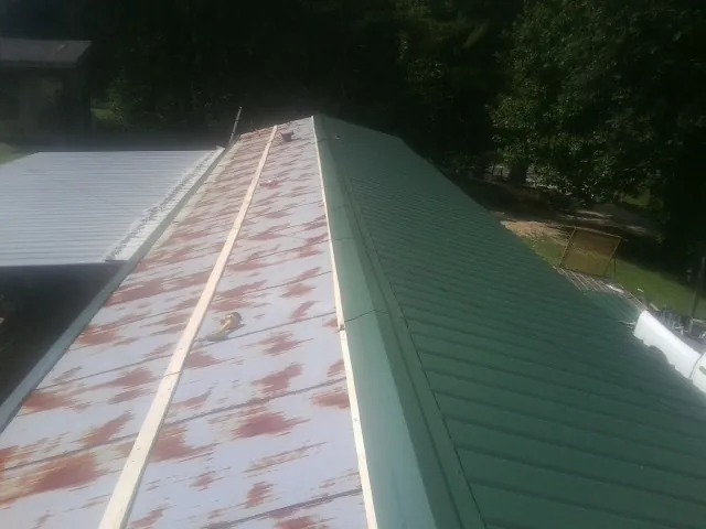 Old rusted panels beside newly installed green metal roofing — Wind Damage Roof Repair by Roofing Brothers in South Acworth