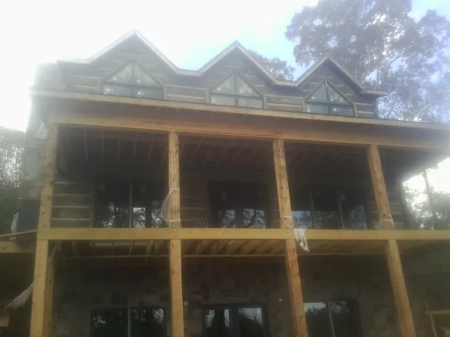 Dormers and porch framing on a large log home under construction — Roof Coating work by our crew in South Acworth