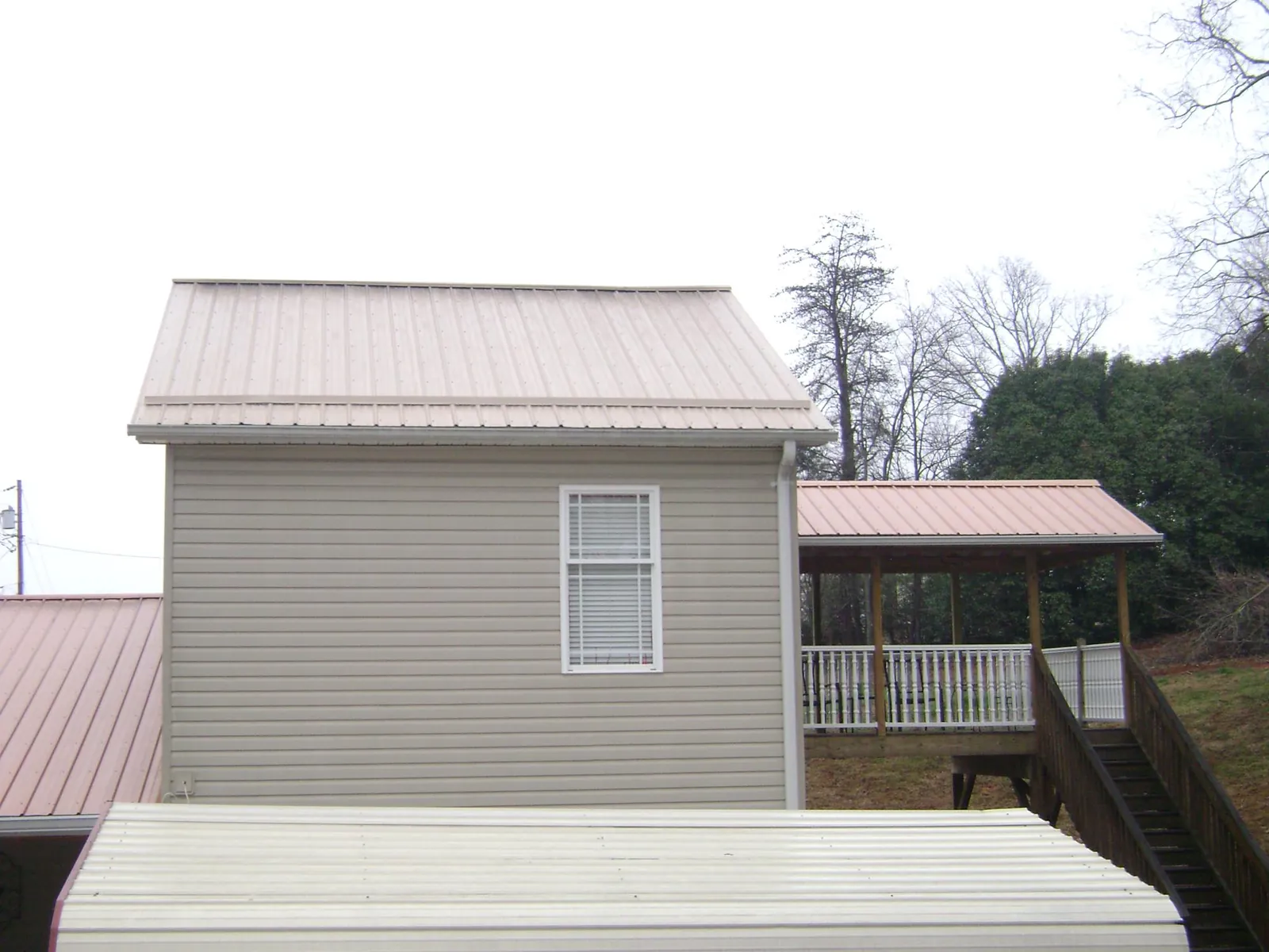 Tan metal roofs on a two story addition and attached porch, from a Roof Replacement job in South Acworth