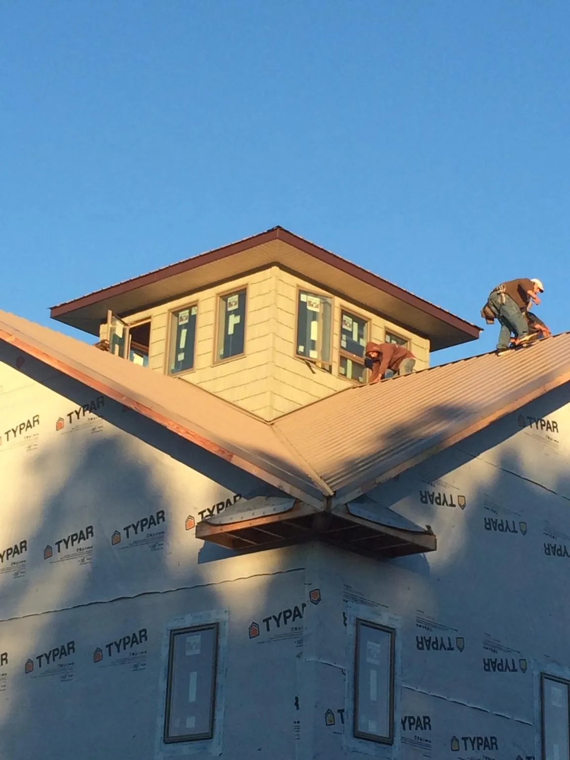 Roofers working around a rooftop cupola on a new metal roof at sunset — Roof Waterproofing in South Acworth by Roofing Brothers